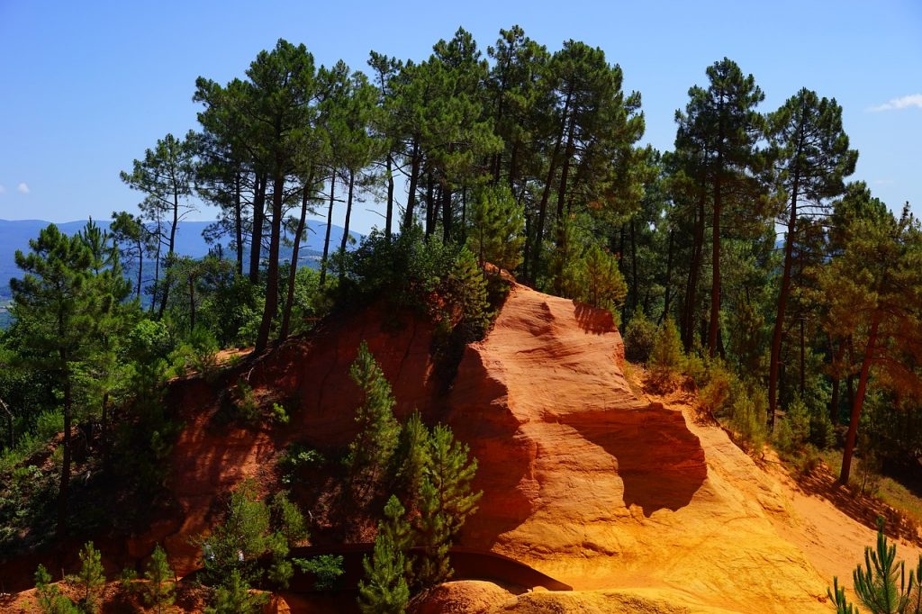 falaise d'ocre avec arbres verts et ciel bleu